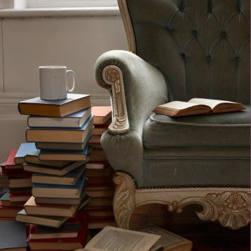 Cozy reading corner with a stack of books and a vintage armchair.