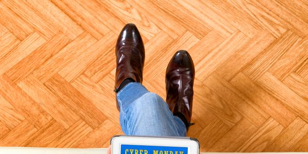 Person wearing brown boots and jeans holding a Cyber Monday sign.