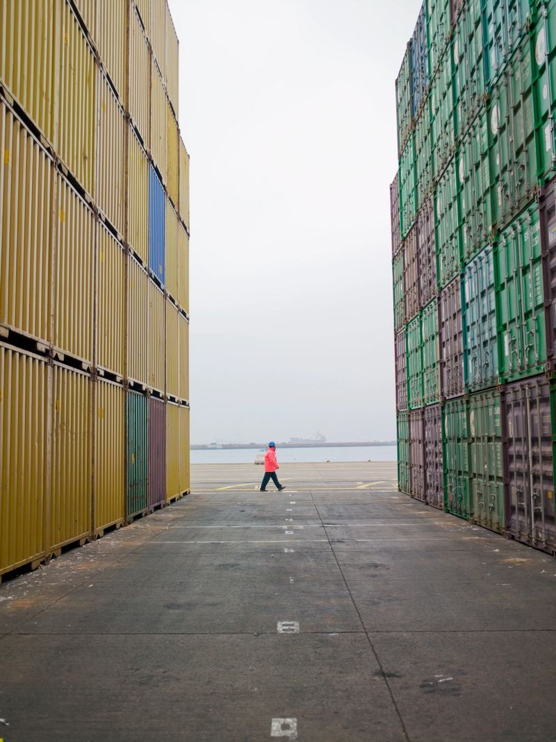 Man standing between containers in a shipping yard