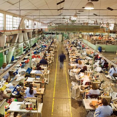Busy shoe factory with workers sewing and assembling footwear.