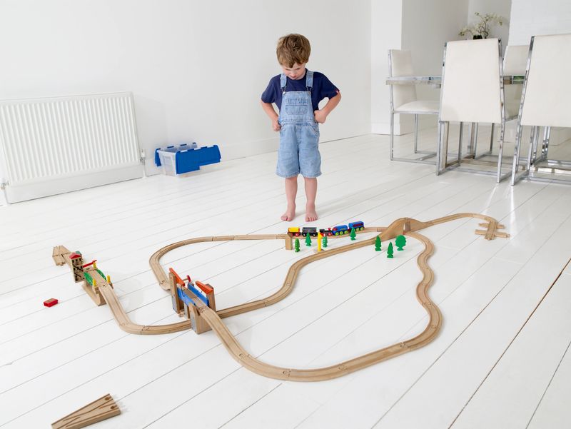 boy of 3 years playing with his train track in modern home space
