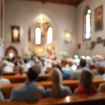 Blurred image of people seated inside a church during a service.