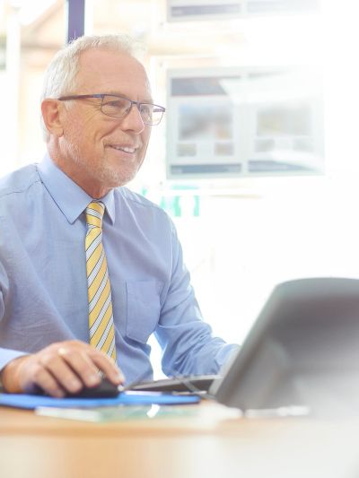 Smiling senior man working on a laptop.