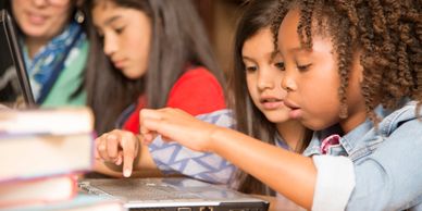 Children engaged in a group activity using a laptop.