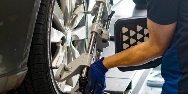 Technician calibrates wheel alignment on a car in a garage.