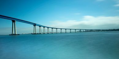 A long bridge stretching over calm blue water under a clear sky.