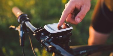 Person using a cycling GPS device on bike handlebar.
