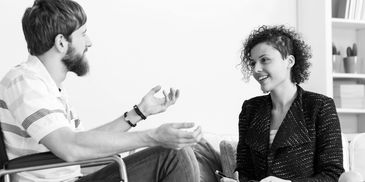 A person using a wheelchair talks with a practitioner taking notes in a calm, supportive setting.
