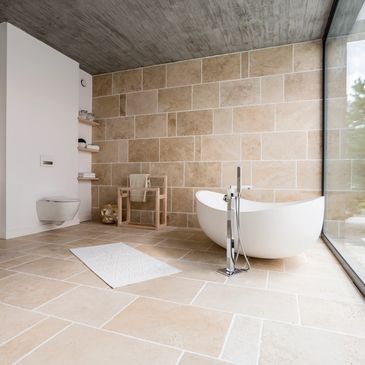 Elegant bathroom with beige tiles, white grout, stone wall, and traditional bathroom tiling
