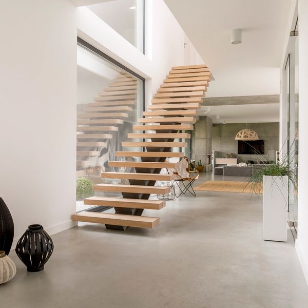 Minimalist interior with floating wooden stairs and decorative vases.