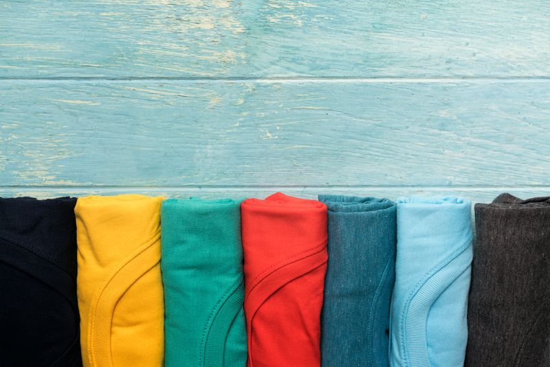close up of rolled colorful clothes on table background