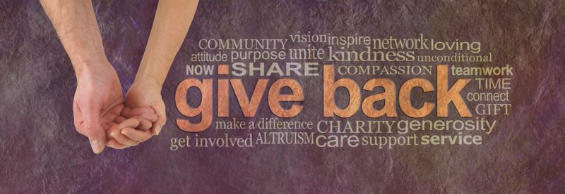 Campaign banner with female hand holding male cupped hand on left and a GIVE BACK word cloud  on right against a rustic parchment background