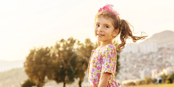 Smiling girl in colorful dress outdoors.