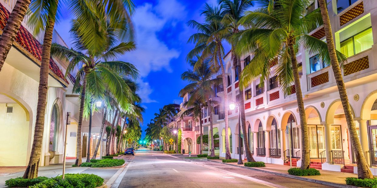 Palm-lined street with Mediterranean-style buildings at twilight.