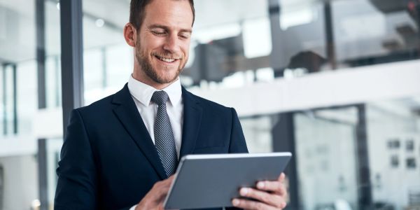 Smiling businessman using a tablet in modern office.