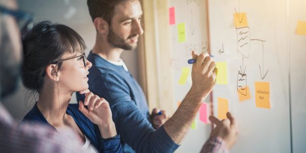 People brainstorming and writing on a whiteboard.