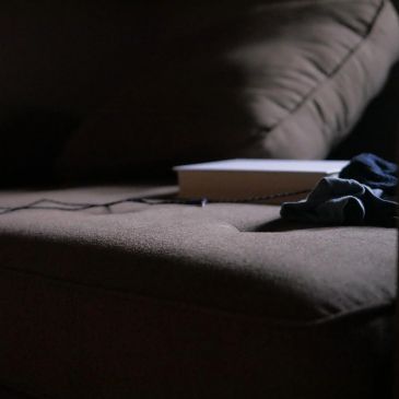 A book and clothes on a cushioned surface in dim light.