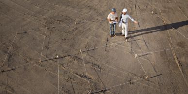Two people inspecting a large cracked surface with measuring tools.