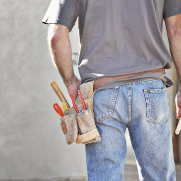 Person wearing a tool belt with tools.