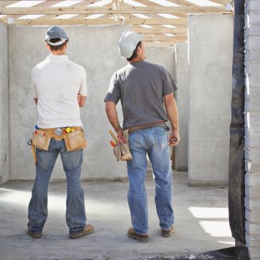 Two construction workers inspecting a building frame.