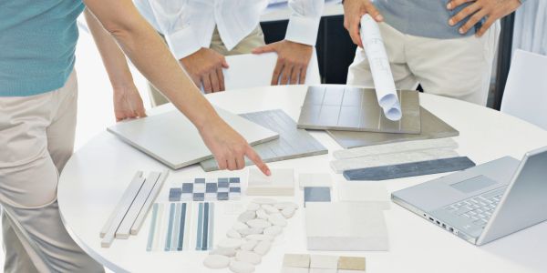 People reviewing tile samples and designs on a table.