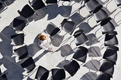 Person sitting inside a heart-shaped arrangement of chairs.