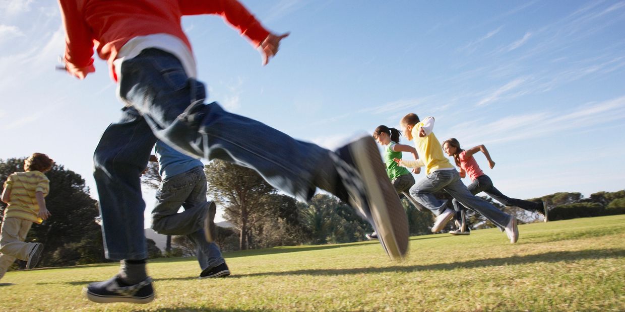 Children running and playing outdoors on a sunny day.