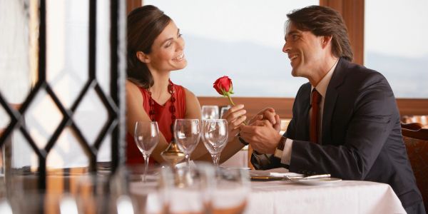 Couple enjoying a romantic dinner with a rose.