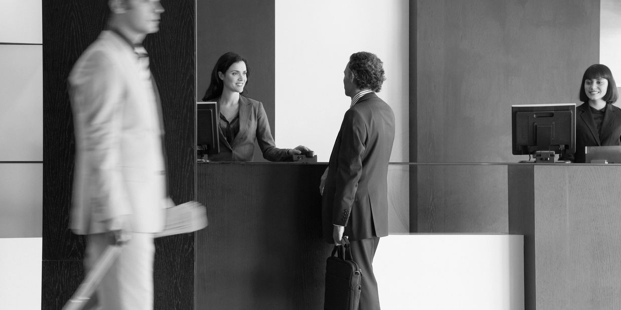 Personal de recepción atendiendo a un huésped durante el registro en un hotel.