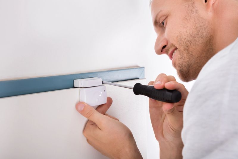 Close-up Of Technician Installing Security System Door Sensor Using Screwdriver