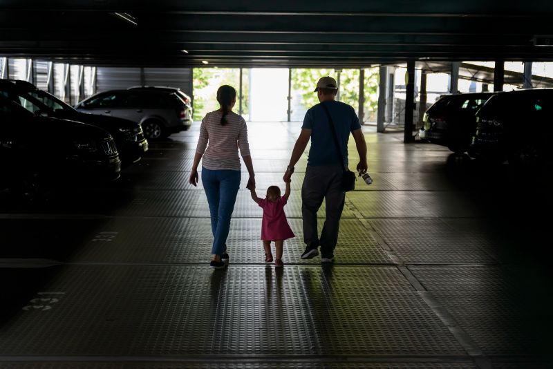 Family mom and dad go through the dark car park at the exit