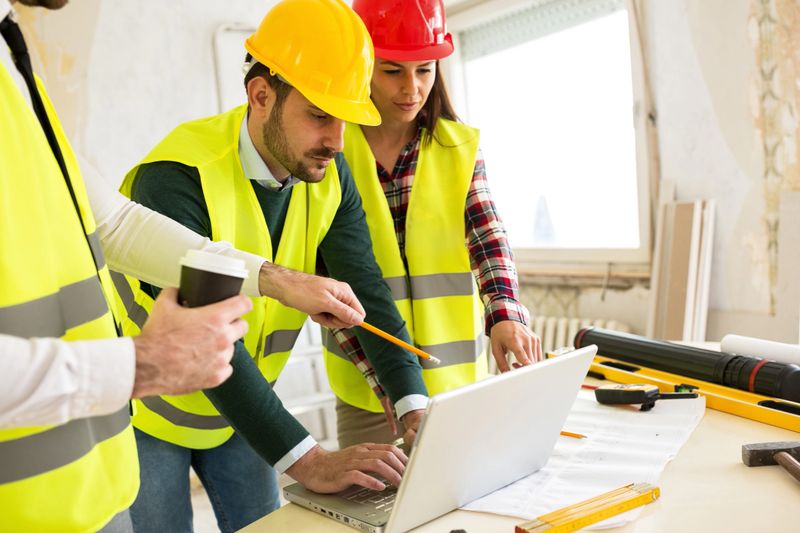 Architects using laptop at construction site, teamwork