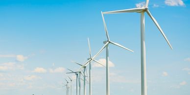A row of wind turbines in a green field under a clear blue sky.