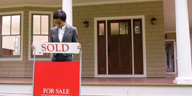 A person inserting a sold sign into a realtor sign frame