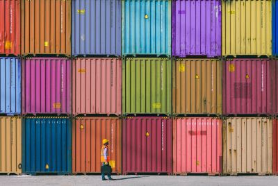 Worker walking in front of colorful shipping containers.