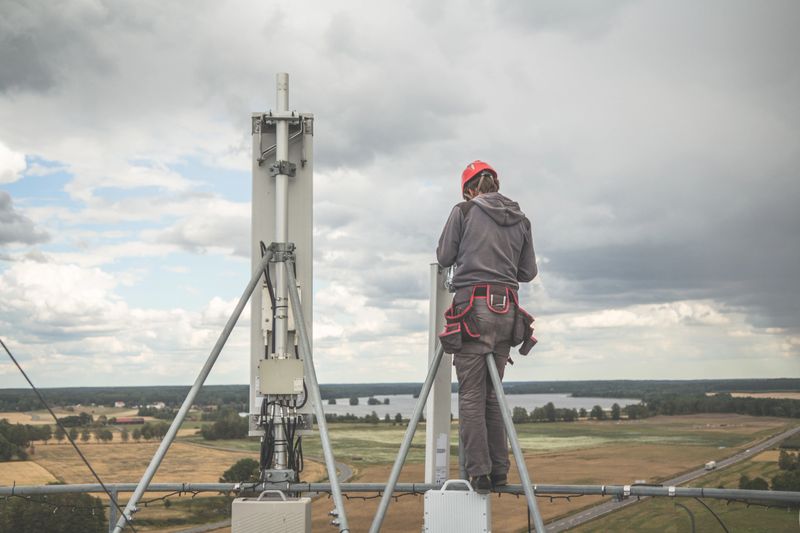 Telecommunication manual high worker engineer installing new 3g 4g LTE antenna on mobile base station (communication tower) located at the top of a water tower. Working at height.