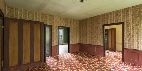 Empty vintage room with floral carpet and patterned wallpaper.