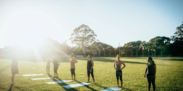 People preparing for outdoor exercise on yoga mats during sunrise.