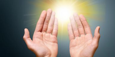 Two hands cupped around a bright glowing light source.