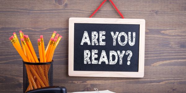 Chalkboard sign saying "ARE YOU READY?" with pencils nearby.