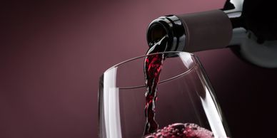 Red wine being poured into a glass against a purple background.