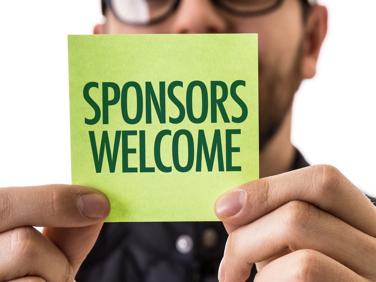 Person holding a green card with 'SPONSORS WELCOME' text.