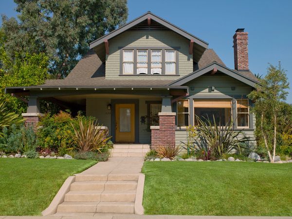 Charming craftsman-style house with green exterior and brick accents.