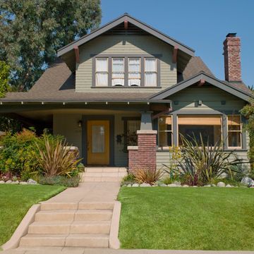 A charming craftsman-style house with a green exterior and a welcoming front porch.