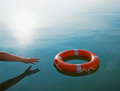 Hand reaching for life buoy in calm water.