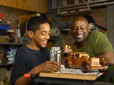 Father and son building a wooden car model together.