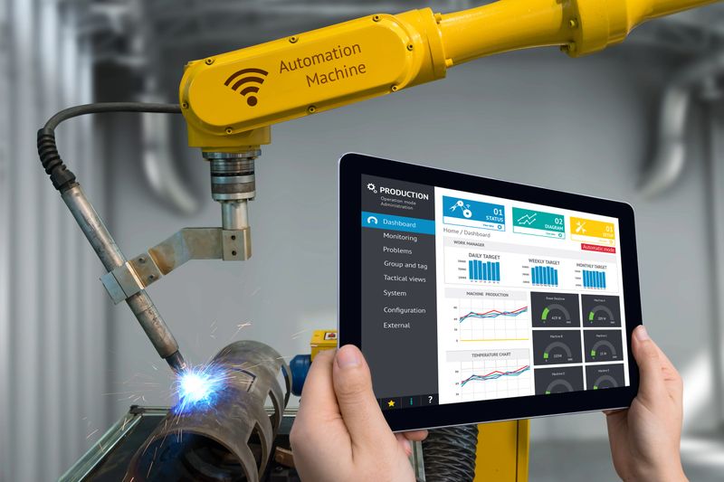 Engineer hand using tablet, heavy automation robot arm machine in smart factory industrial with tablet real time monitoring system application. Industry 4th iot concept.