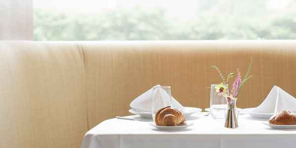 Elegant restaurant table setting with croissants and flowers.