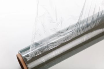A roll of transparent plastic wrap partially unrolled.