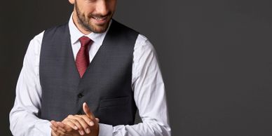 Man in a dark vest and red tie smiling against a gray background.